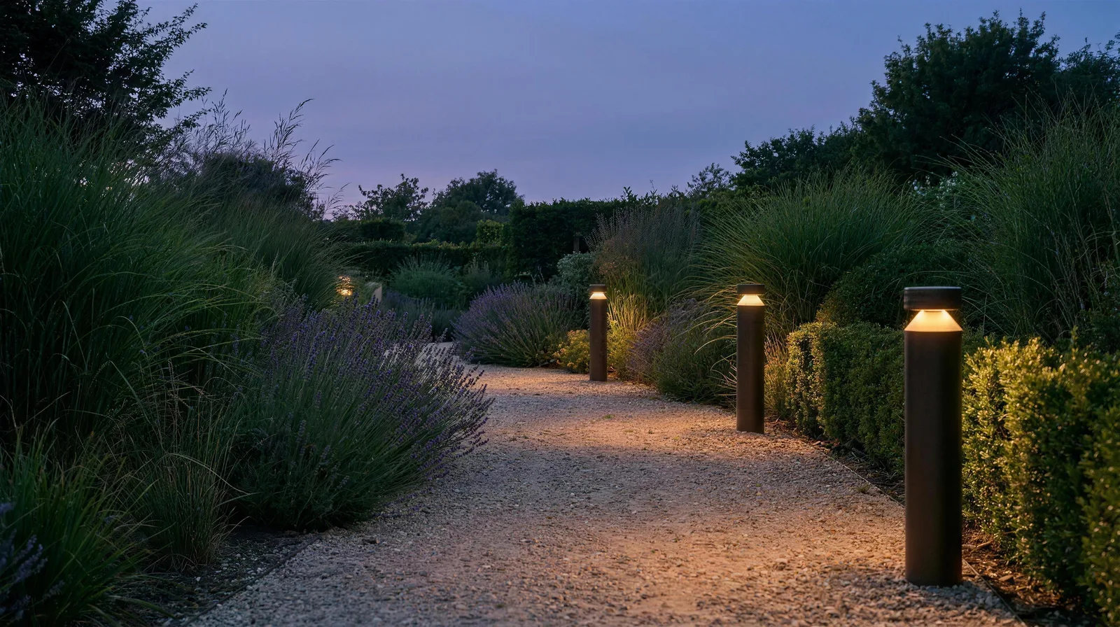 Allée de jardin au crépuscule, bordée de bornes solaires allumées à la lumière ambrée
